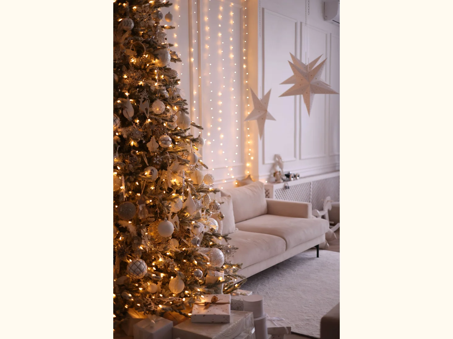 A Christmas tree standing beside a sofa in a living room.