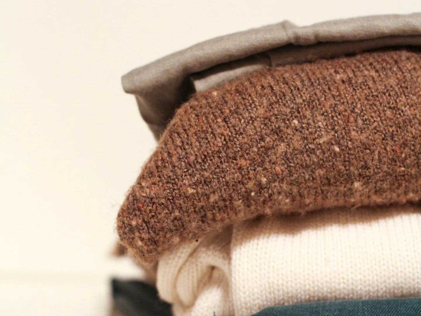 A stack of folded sweaters showing their knit textures.
