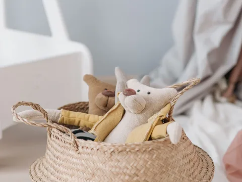 Soft toys kept together in a woven storage basket.