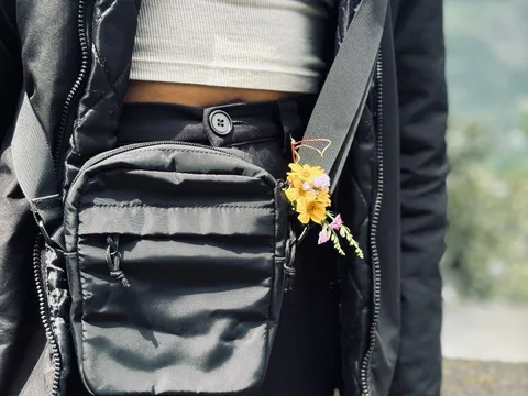 A black crossbody bag worn over a casual outdoor outfit.