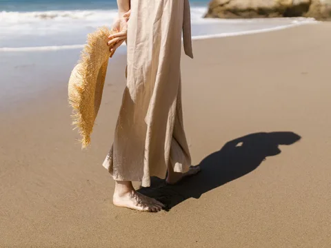 Beige linen trousers worn on a sandy beach.