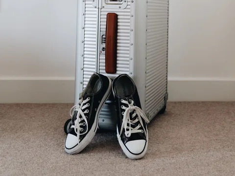 A pair of canvas sneakers beside a suitcase.